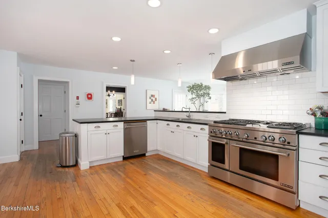a kitchen with stainless steel appliances a stove and white cabinets