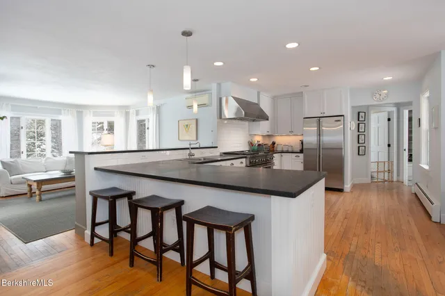a kitchen with stainless steel appliances a dining table chairs and wooden floor