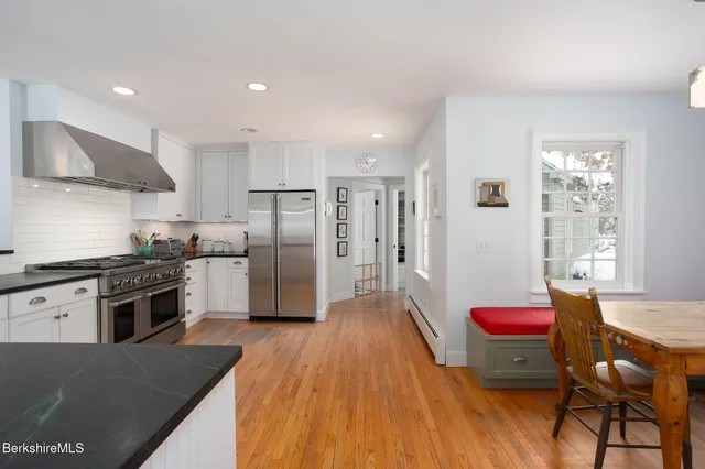 a kitchen with refrigerator a stove a sink dishwasher with a dining table and chairs