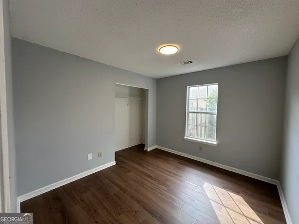 an empty room with wooden floor and windows