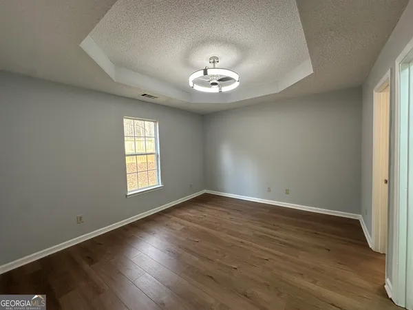an empty room with wooden floor and windows