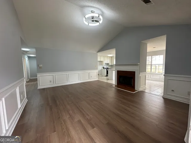 an empty room with wooden floor fireplace and windows
