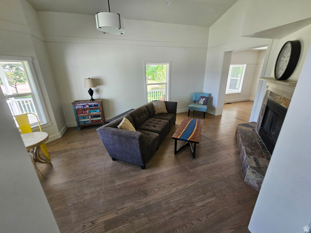 812 East Bates Cyn Road Tooele, UT 84074 - Photo 12 of 144 Spacious living area featuring wood-finish flooring, a corner fireplace with stone surround, and abundant natural light from multiple windows