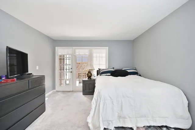 a spacious bedroom with a bed and a flat tv screen on dresser