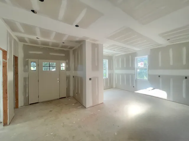 a view of an empty room with a window and a kitchen