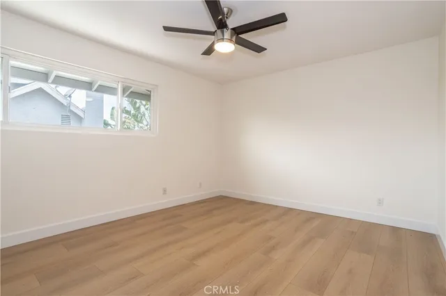 an empty room with a window and a ceiling fan