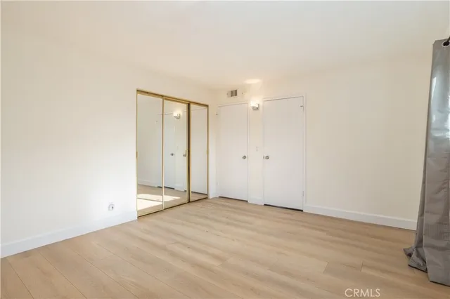an empty room with wooden floor and mirror
