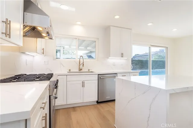 a kitchen with a sink a stove a refrigerator and white cabinets