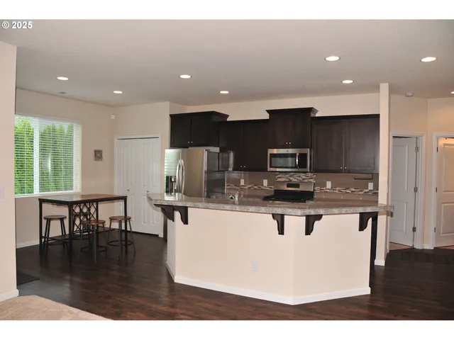 a view of kitchen with kitchen island stainless steel appliances a stove a sink a refrigerator and a dining table