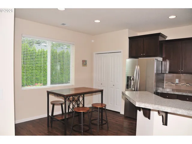 a kitchen with stainless steel appliances a dining table chairs and a refrigerator