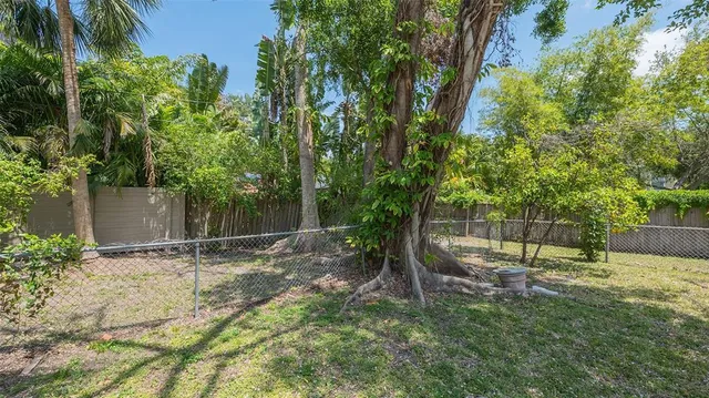 a view of a backyard with wooden fence and large trees