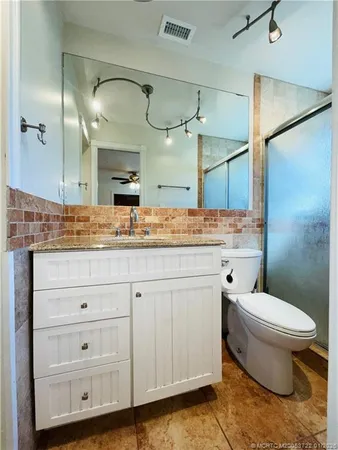 a bathroom with a granite countertop sink mirror vanity and toilet
