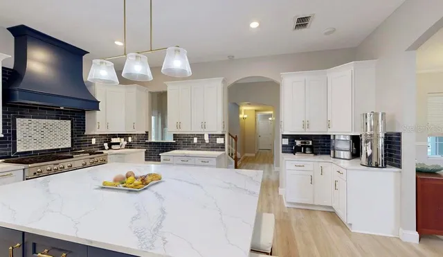 a living room with furniture kitchen view and a chandelier