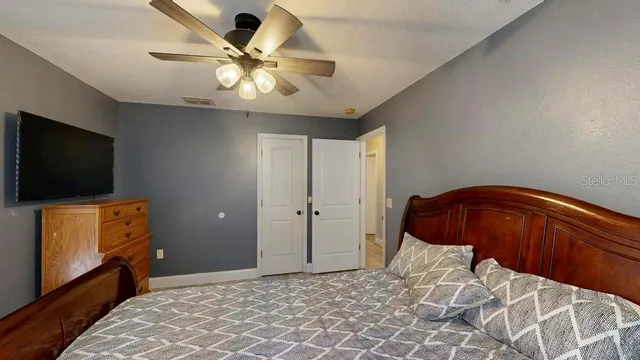 a bedroom with a bed and a flat tv screen on the dresser