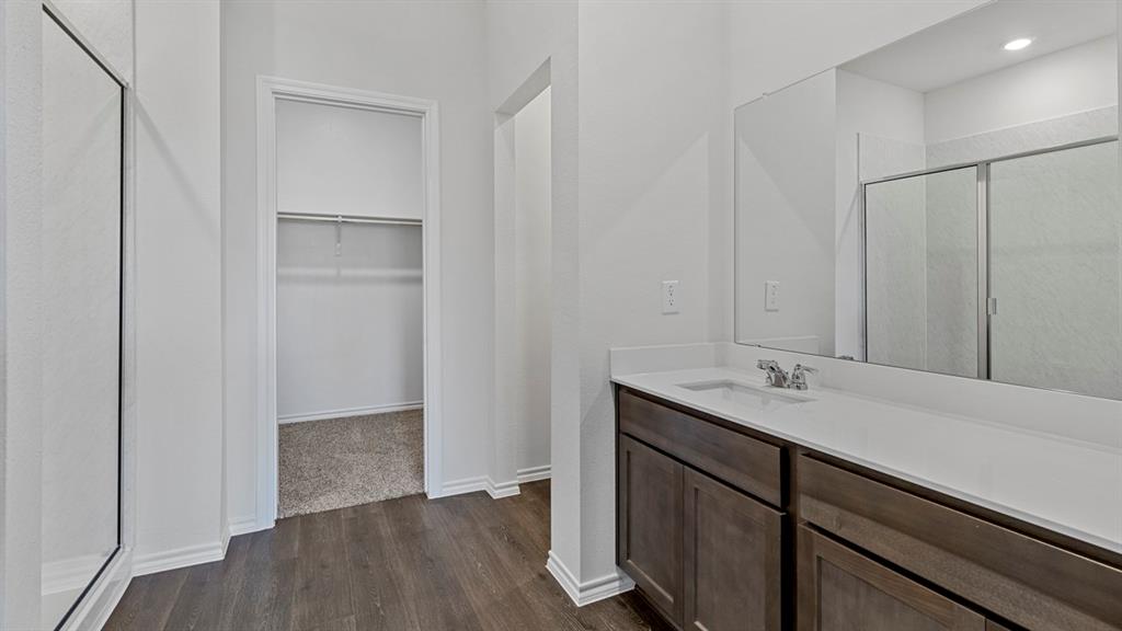 212 Pheasant Run Road Terrell, TX 75160 - Photo 15 of 24 Dual vanity with a white countertop and undermount sink, wood-finish flooring, and a walk-in shower with a glass enclosure