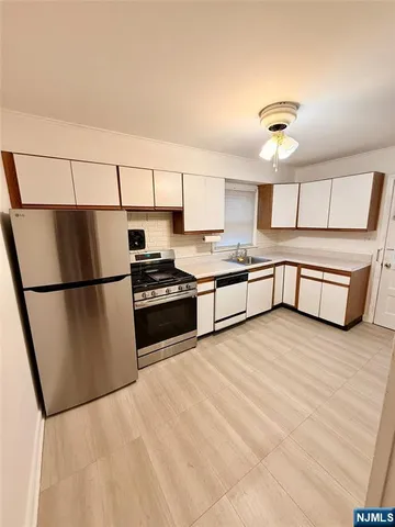 a kitchen with stainless steel appliances granite countertop a refrigerator a stove and a sink