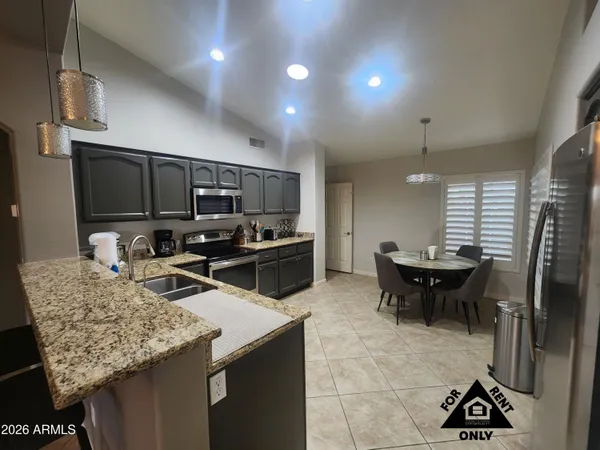 a kitchen with a sink stainless steel appliances and chairs