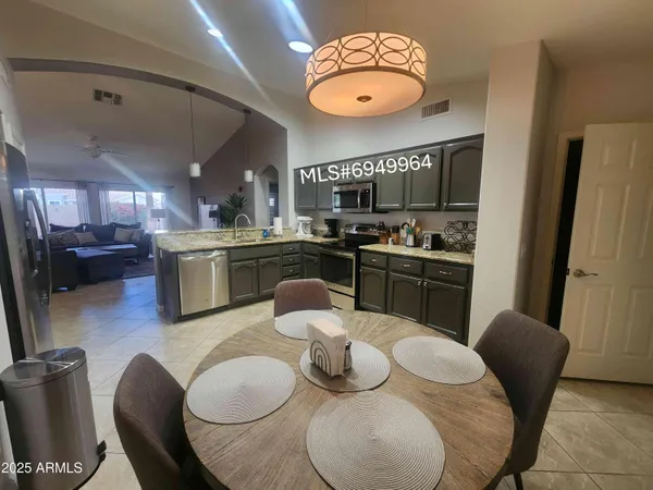 a kitchen with stainless steel appliances granite countertop a dining table and chairs