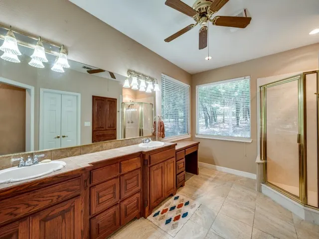 a spacious bathroom with a double vanity sink a large mirror and a shower