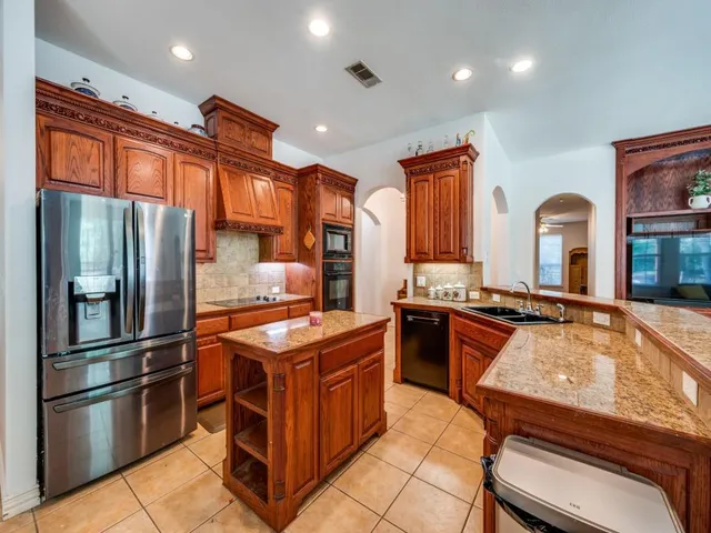 a kitchen with stainless steel appliances granite countertop a stove a refrigerator and a stove top oven