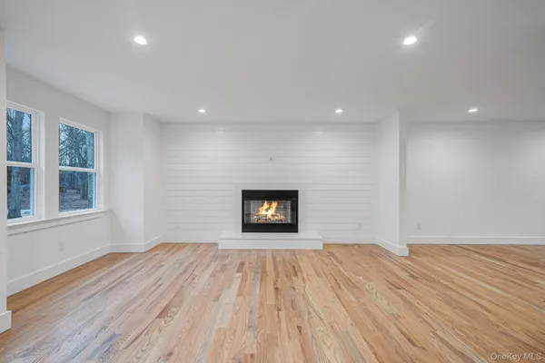 a view of empty room with wooden floor and kitchen