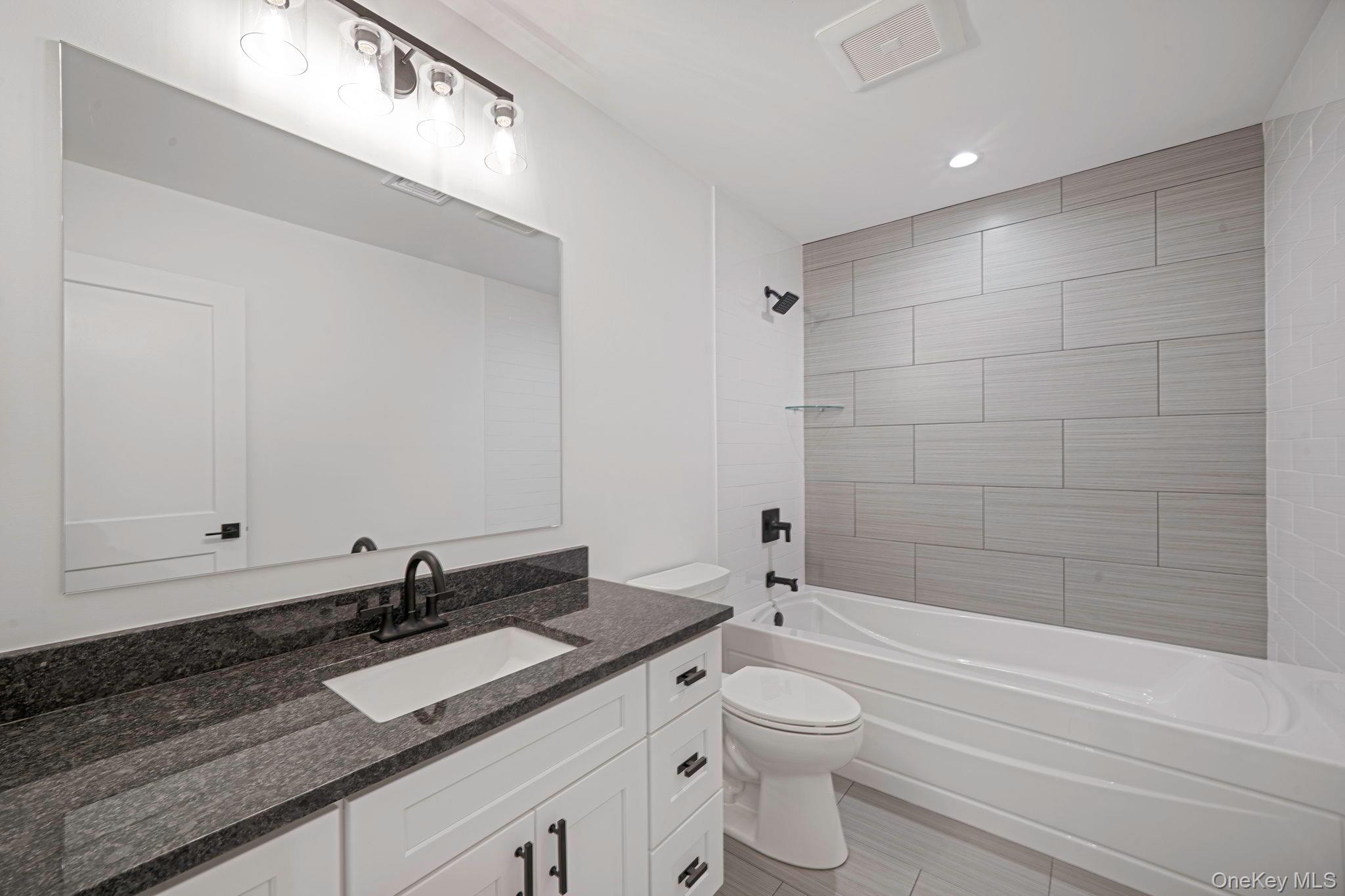 63 A Blydenburgh Road Centereach, NY 11720 - Photo 22 of 38 a bathroom with a granite countertop sink a toilet and bathtub