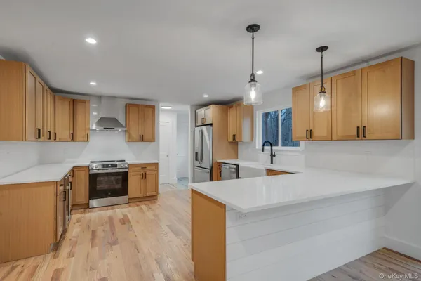 a large kitchen with stainless steel appliances kitchen island a large counter top a stove a sink cabinets and a wooden floor