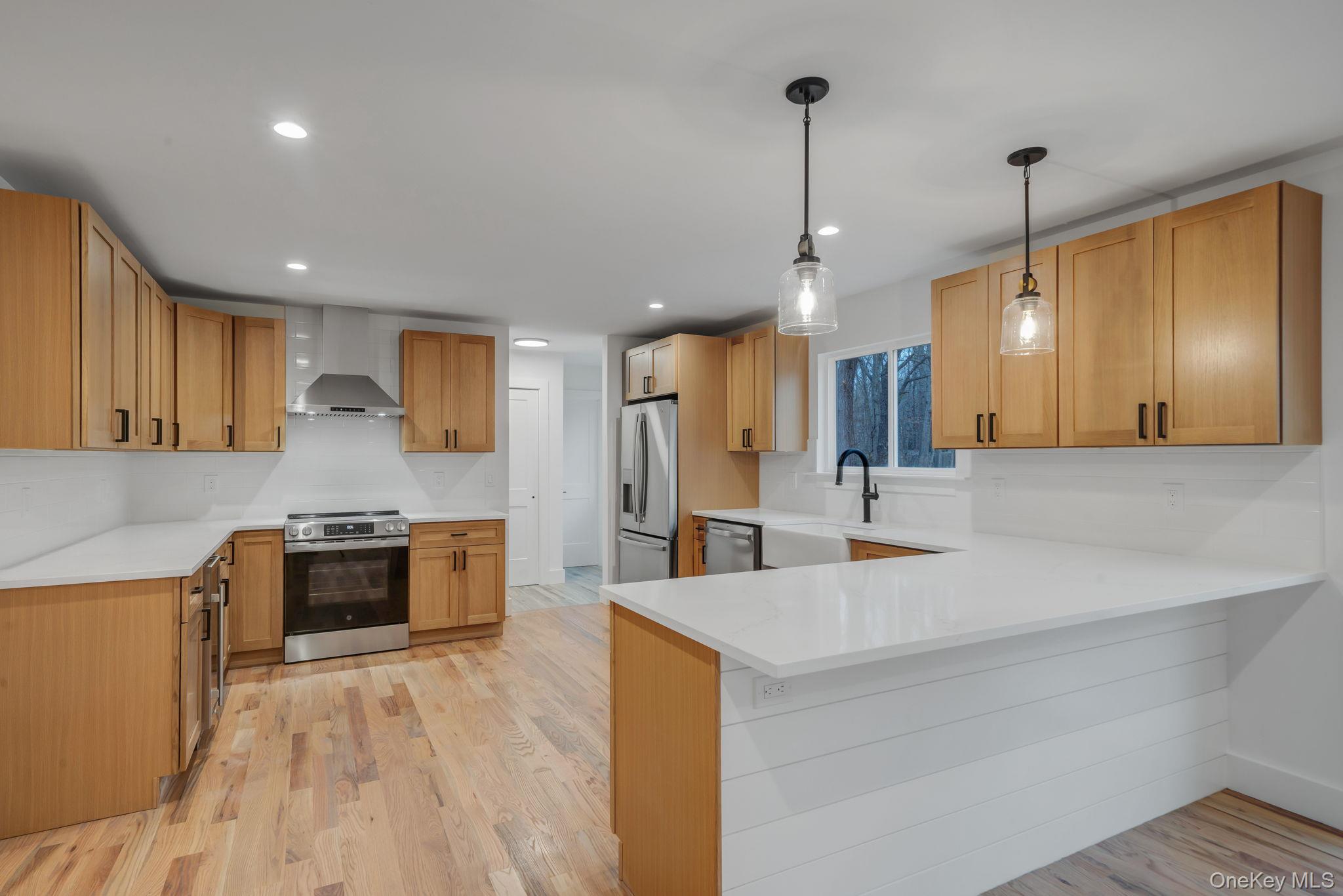 63 A Blydenburgh Road Centereach, NY 11720 - Photo 4 of 38 a large kitchen with stainless steel appliances kitchen island a large counter top a stove a sink cabinets and a wooden floor
