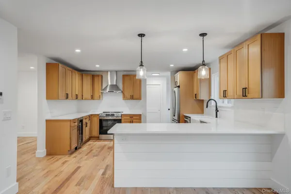 a large kitchen with kitchen island a stove a sink a center island and wooden floor