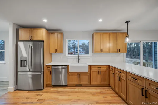 a large kitchen with stainless steel appliances granite countertop a refrigerator a sink a stove and a wooden floors