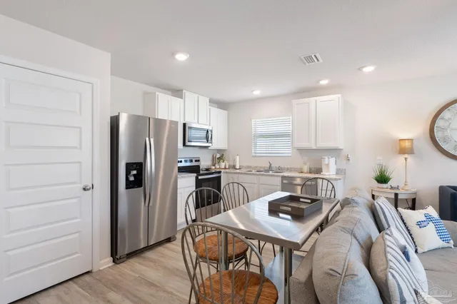a kitchen with stainless steel appliances a table chairs refrigerator and cabinets