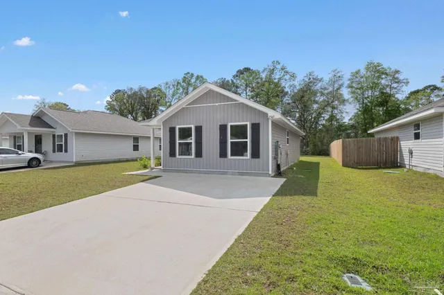 a front view of house with yard and trees in the background