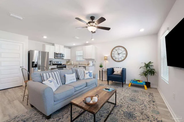 a living room with furniture a clock on wall and a flat screen tv