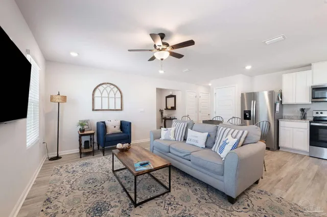 a living room with furniture a ceiling fan and a flat screen tv
