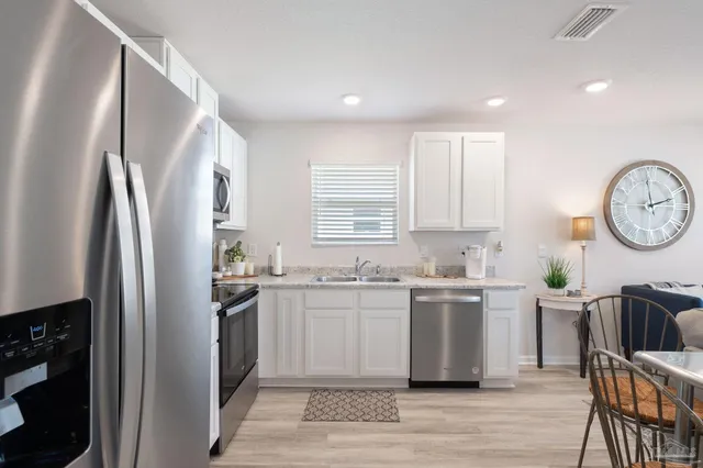 a kitchen with stainless steel appliances granite countertop a refrigerator a stove a sink a dining table and chairs