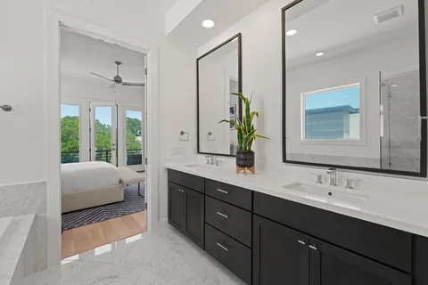 a spacious bathroom with a double vanity sink a large mirror and a bathtub