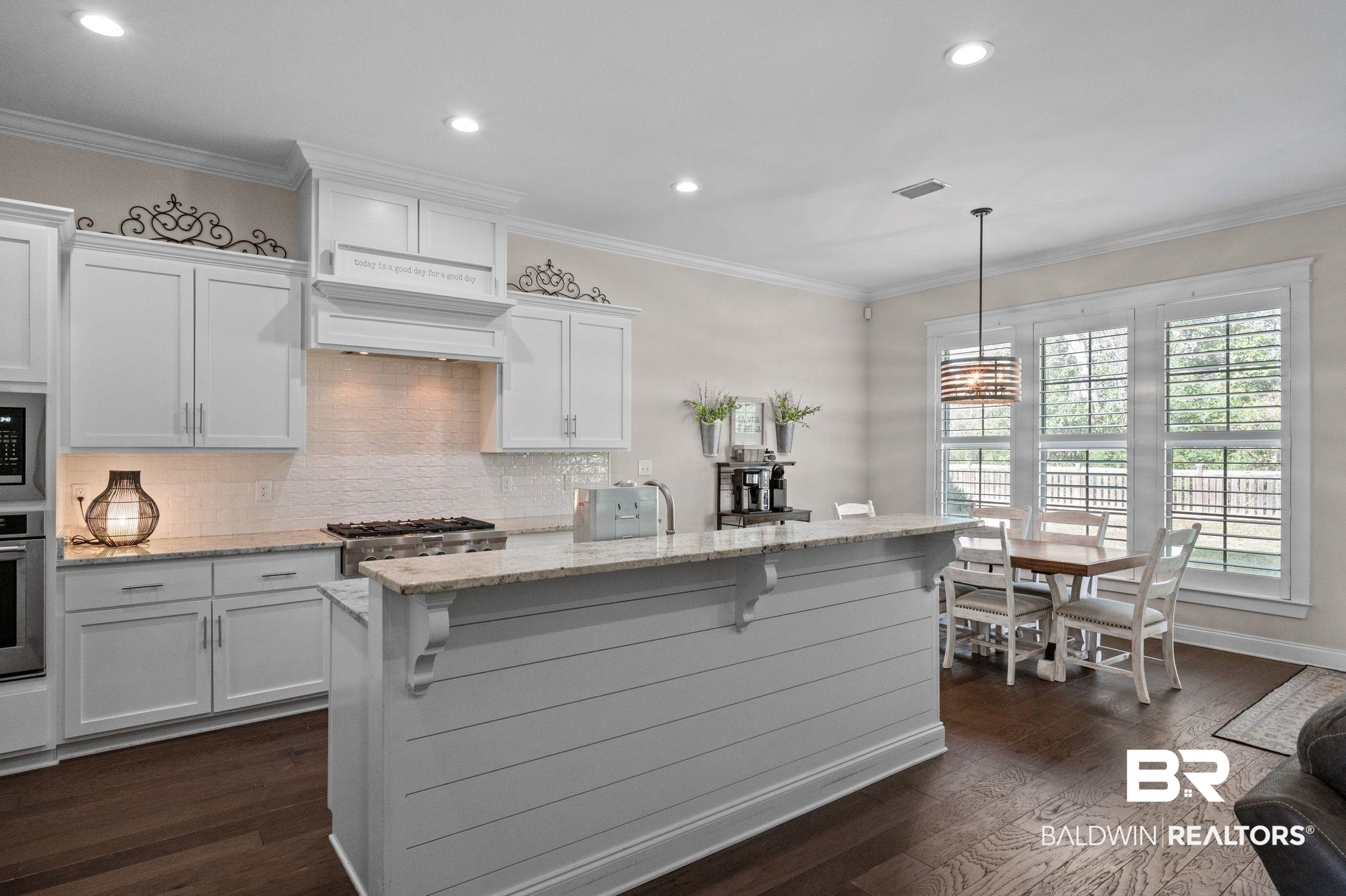 32194 Badger Court Daphne, AL 36527 - Photo 13 of 49 Kitchen with white cabinetry, light stone counters, a breakfast bar area, backsplash, and decorative light fixtures