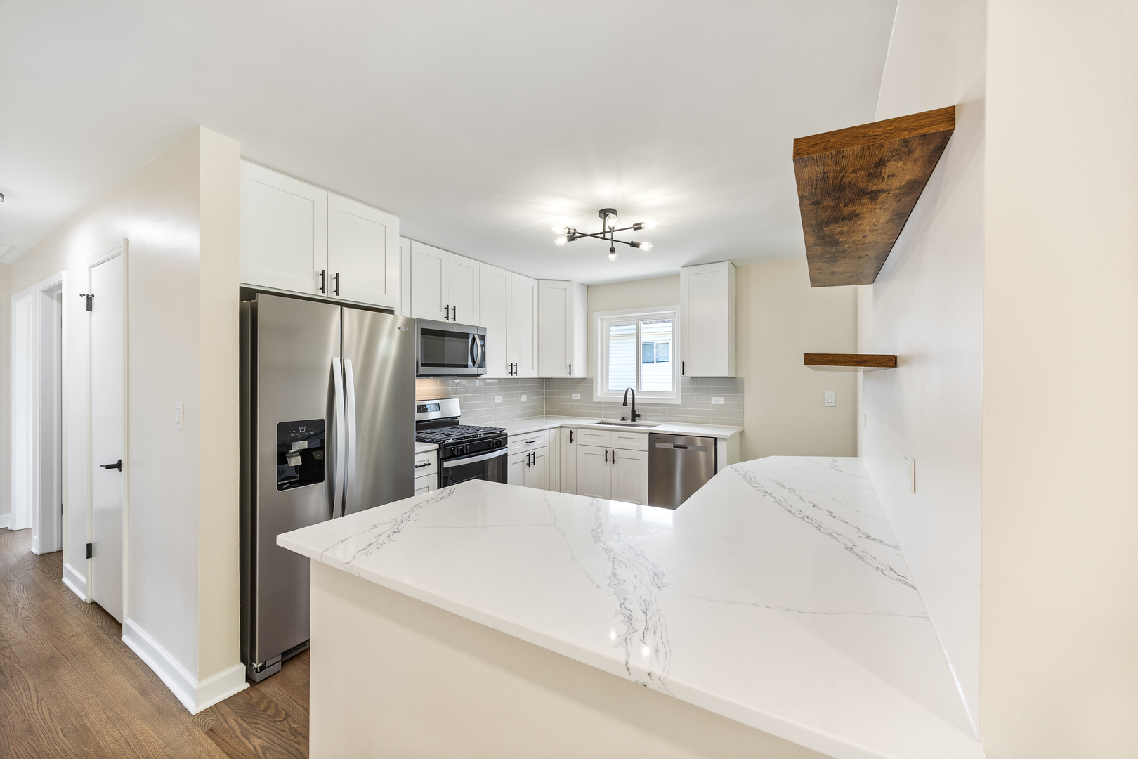 5821 Warren Street Morton Grove, IL 60053 - Photo 12 of 27 a large white kitchen with cabinets a refrigerator and a fireplace