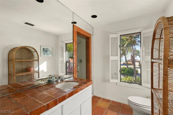 a bathroom with a granite countertop tub sink toilet window and mirror