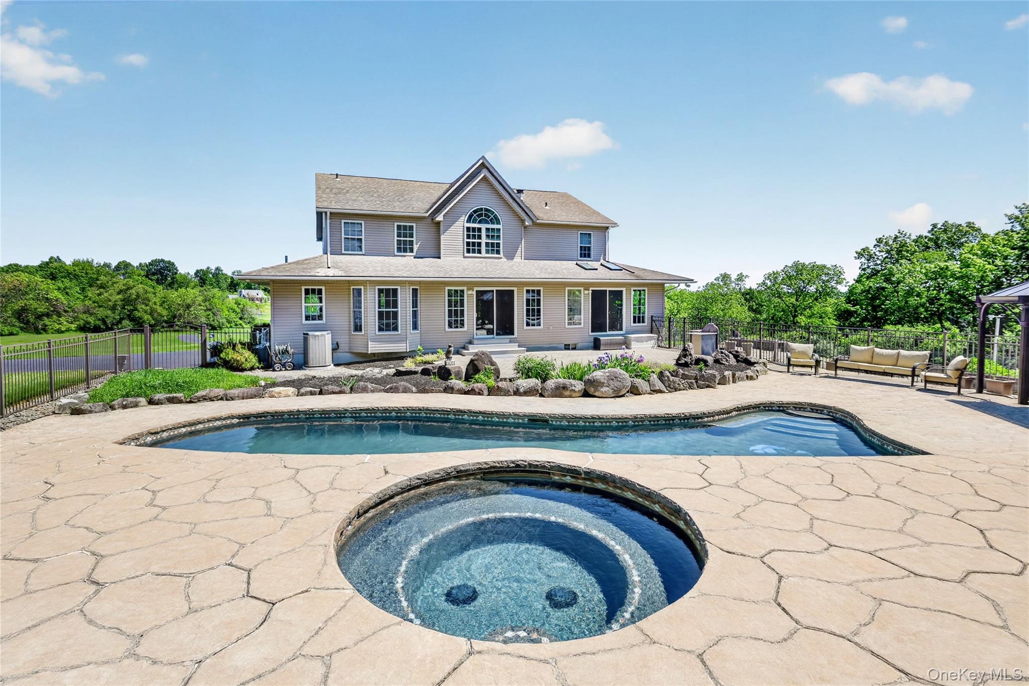954 Ridgebury Road New Hampton, NY 10958 - Photo 39 of 45 From this angle, the resort-like pool area truly shines, with the heated gunite pool, raised hot tub, and waterfall features creating the perfect backdrop for summer days, evening swims, and memorable gatherings at home.
