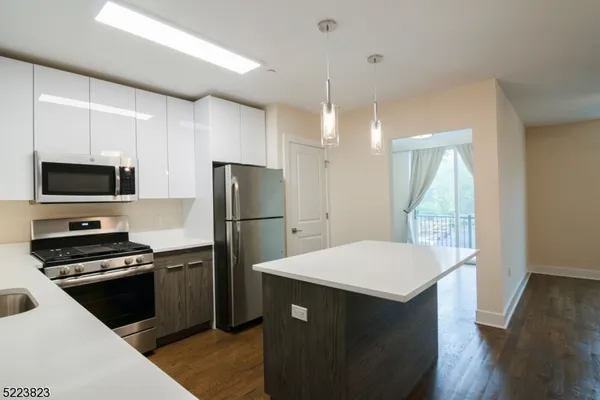 a kitchen with a refrigerator a microwave oven a sink and dishwasher with wooden floor