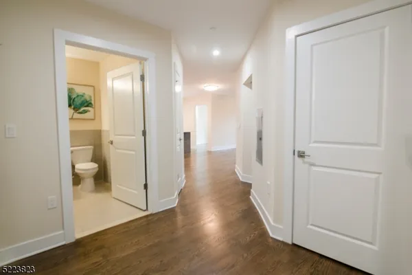 a view of a hallway with wooden floor and a bathroom