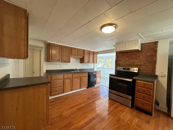 a kitchen with granite countertop a stove cabinets and wooden floor