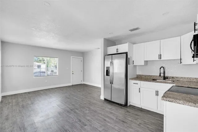 a kitchen with granite countertop a refrigerator and a stove top oven