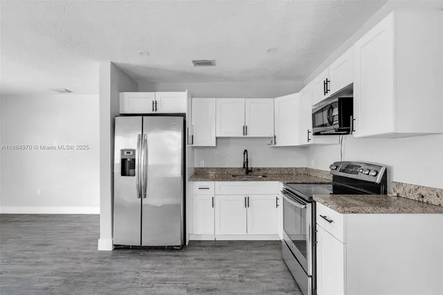 a kitchen with stainless steel appliances granite countertop a stove top oven a refrigerator a sink and dishwasher