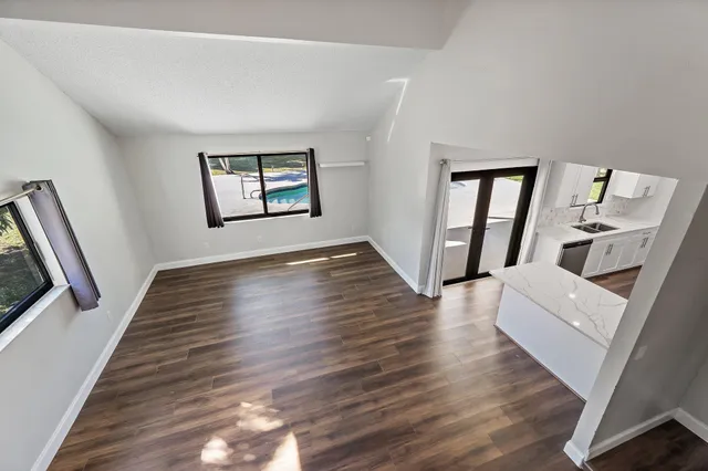 an empty room with wooden floor fan and windows