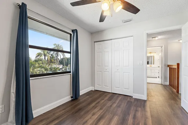 an empty room with wooden floor chandelier fan and windows