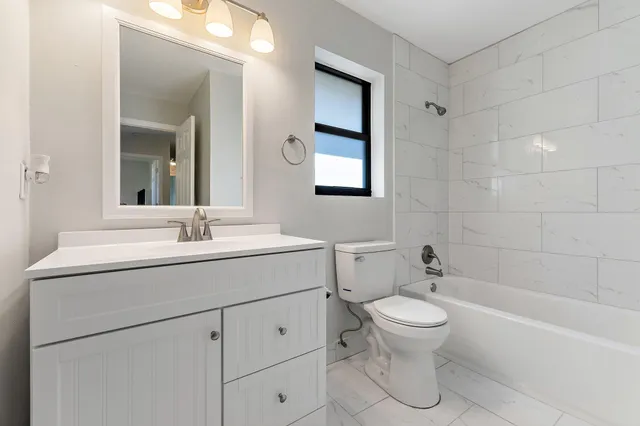 an empty room with wooden floor chandelier fan and windows