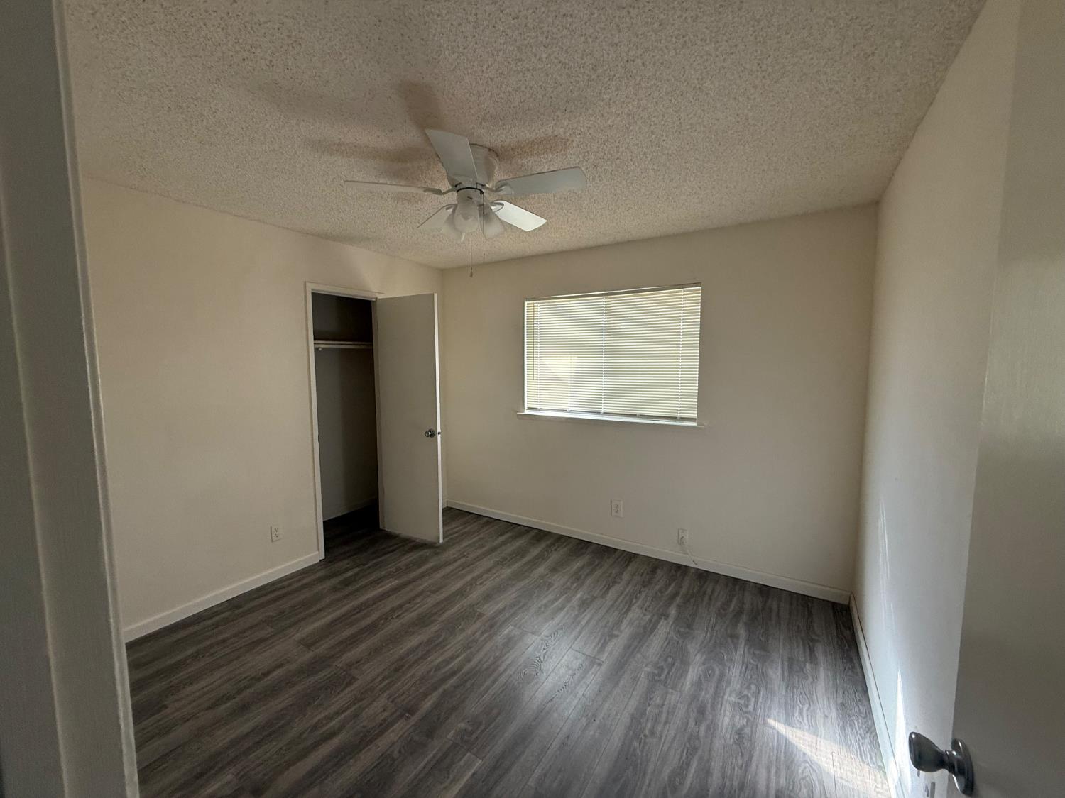 16385 North D Street Madera, CA 93638 - Photo 12 of 26 an empty room with wooden floor chandelier fan and windows