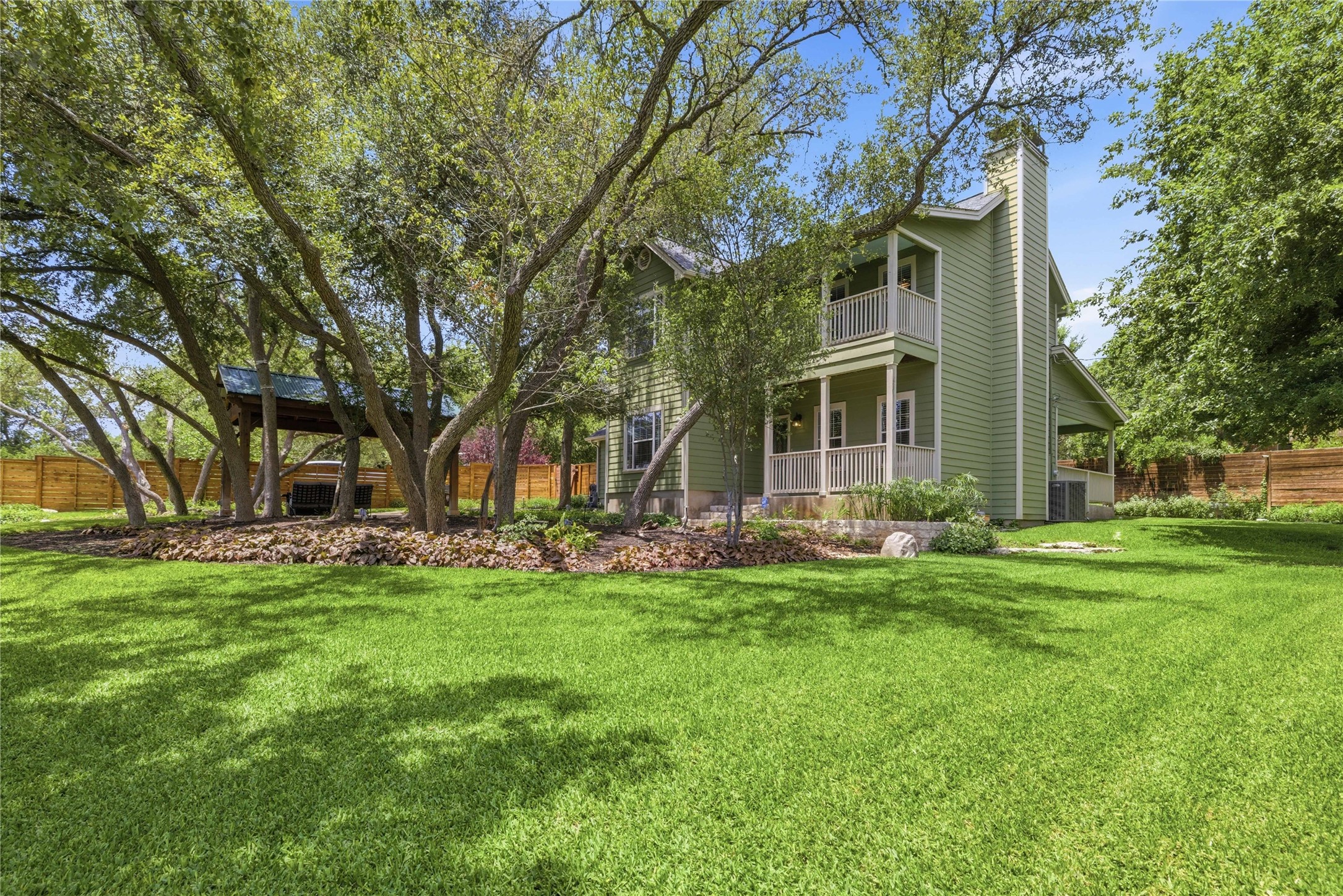 1204 Orlando Road Austin, TX 78733 - Photo 1 of 40 Green siding home with inviting porches and a spacious, verdant yard shaded by mature trees.